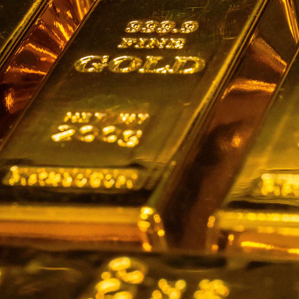 A gold bar stamped 999.9 Fine Gold resting on other bars