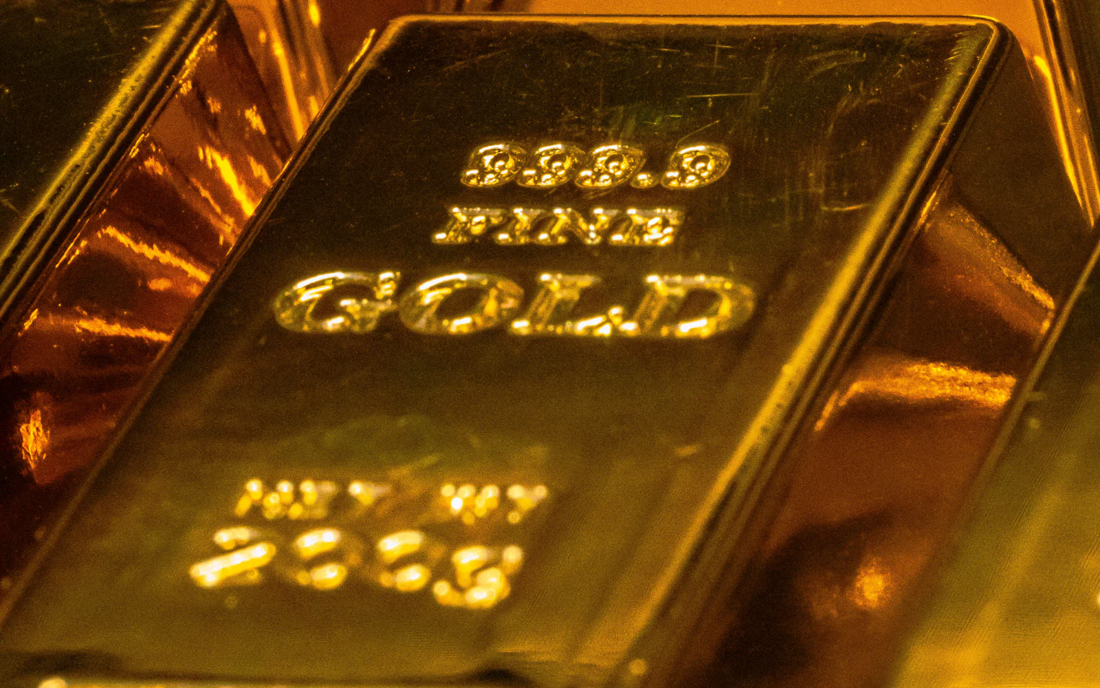 A gold bar stamped 999.9 Fine Gold resting on other bars