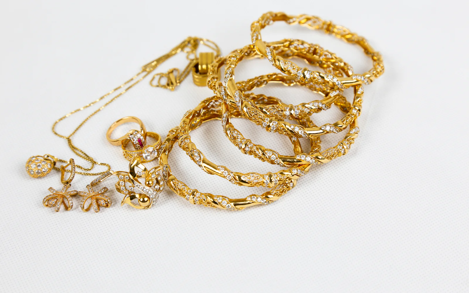Gold chains and bracelets on a white surface